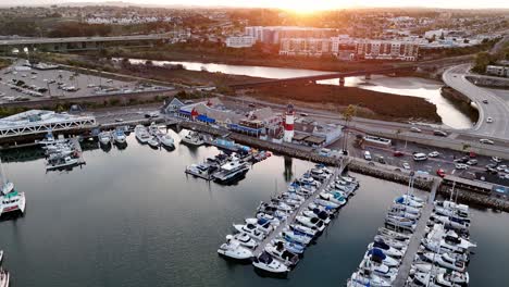 oceanside harbor with boats docked at sunrise, calm waters reflecting light, aerial view