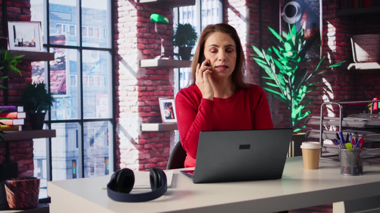 Woman on phone at desk with laptop