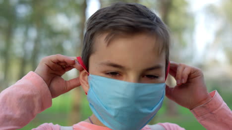 teen boy wearing medical mask outdoors. young guy protecting from covid19.