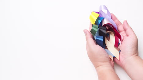 Male-hand-holding-various-colored-ribbons-on-white-background