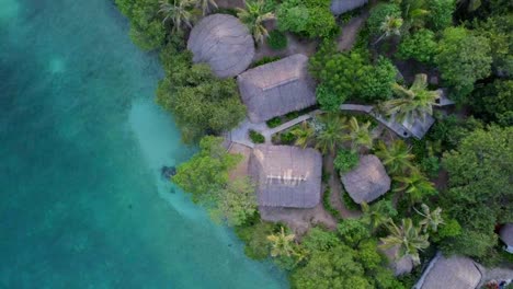 exotic thatched-roof bungalows on turquoise crystal water in caribbean island