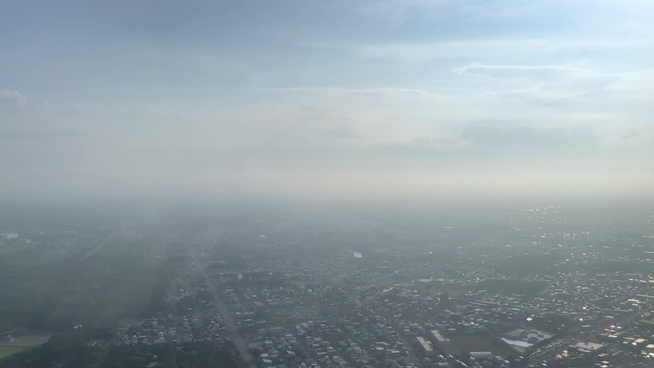 Aerial view of hazy cityscape under sunny sky, evoking tranquility