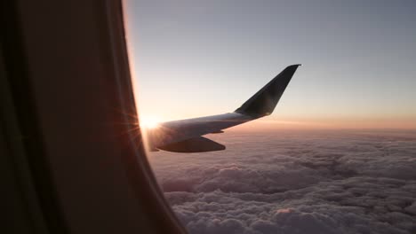 revelación parcial del sol del ala del avión en el horizonte con la llamarada del sol sobre el ala en una hermosa puesta de sol de color naranja magenta suave