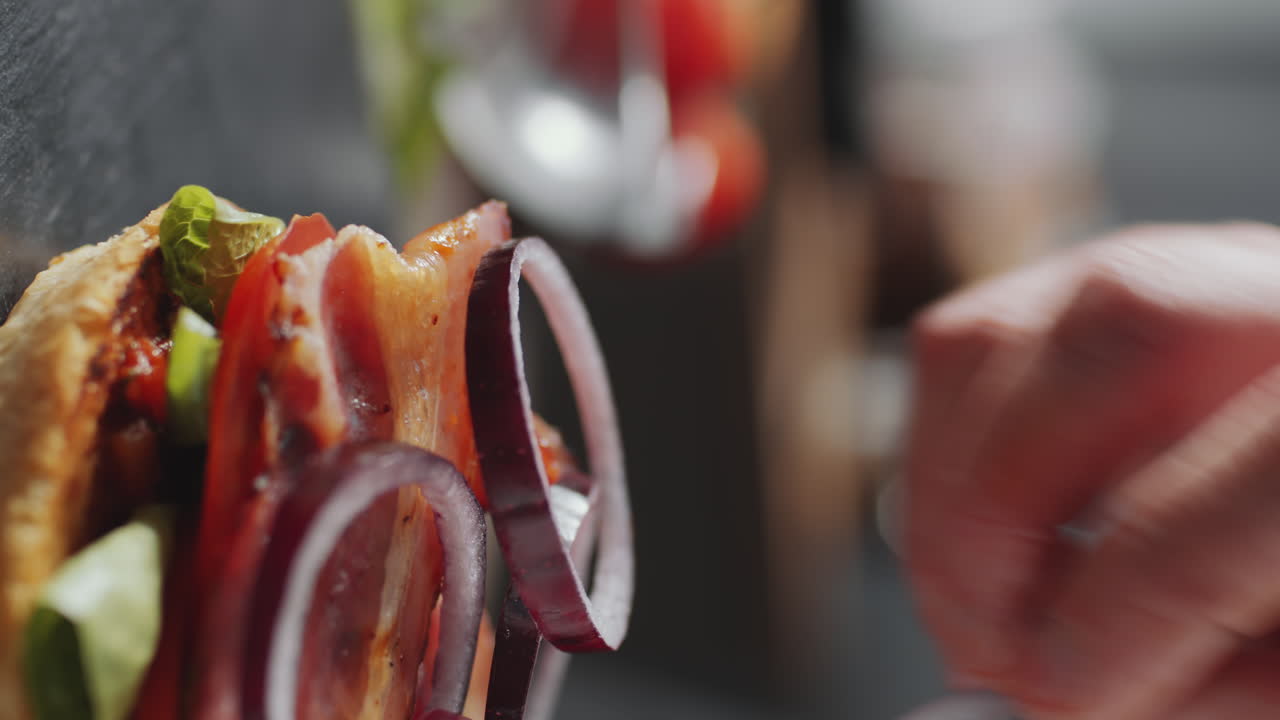 poniendo cebollas rojas en rodajas en la hamburguesa