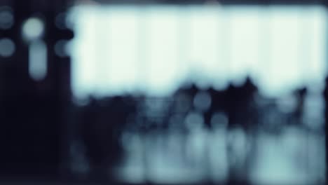 a defocused shot of many silhouettes of people walking around in a food court office building