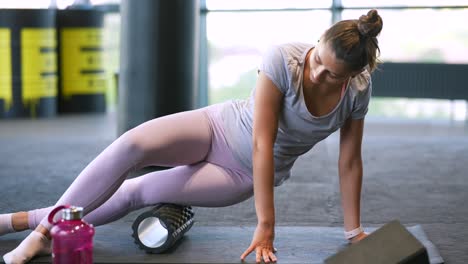 woman foam rolling her leg in a gym.