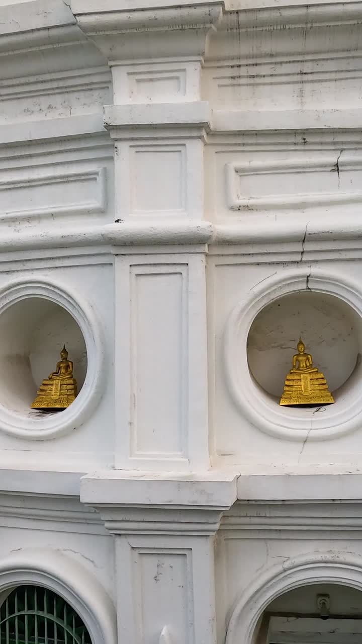 Aerial footage of Wat Prayurawongsawas Worawihan's ornate white facade with golden details, captured in natural daylight, showcasing architectural beauty