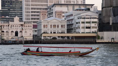 longboat viaja más allá de los edificios de la ciudad y la vegetación