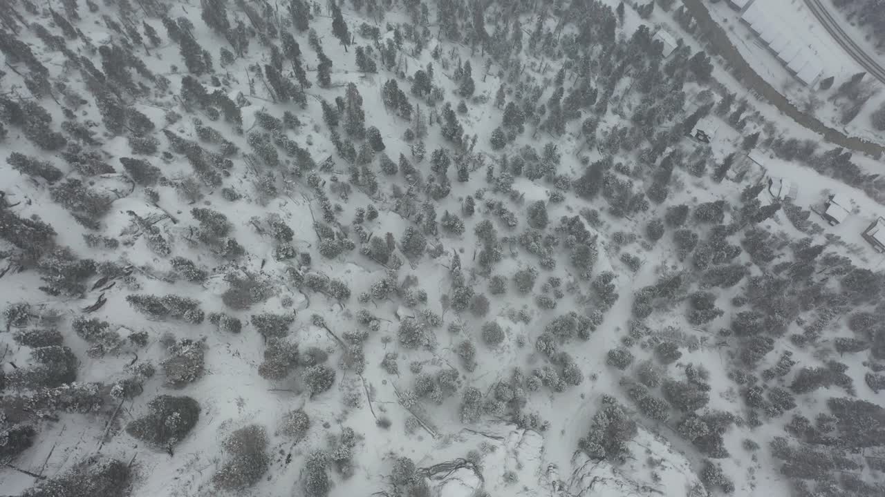 vista aérea de pájaro de ventisca sobre empinadas colinas nevadas y caminos rurales