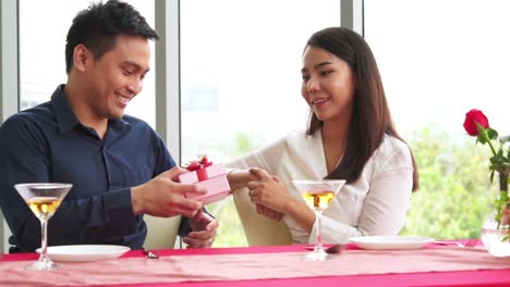 romantic couple giving gift to lover at restaurant