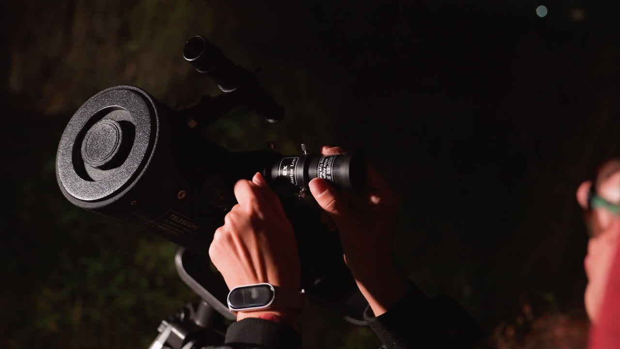Ajuste del ocular de un telescopio en un patio trasero de noche: un astrónomo aficionado ajusta el ocular bajo un cielo tenue, sus manos afinan el enfoque de la óptica, el trípode brilla con el rocío, calma, concentración y curiosidad, afición por la ciencia