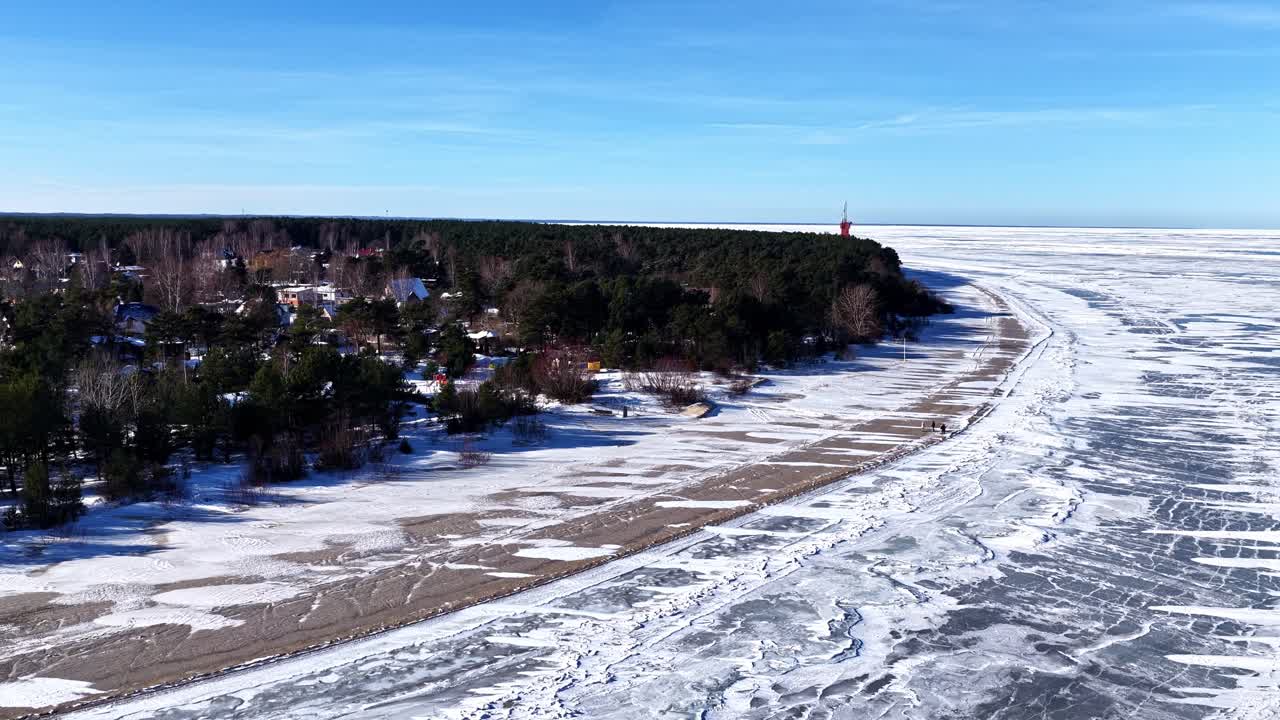 Vue étendue d'une mer gelée, avec de la glace fissurée s'étendant jusqu'à une lisière de forêt lointaine.