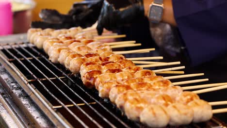 vendor grilling sausages on skewers in bangkok