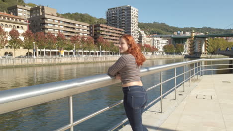 woman enjoying the cityscape by the river on an autumn day
