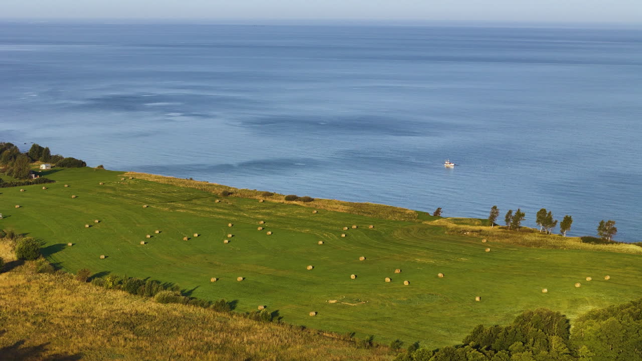Aerial establishing overview of Strante Ulmale coastline, lush green fields, and winding shorelines in Latvia
