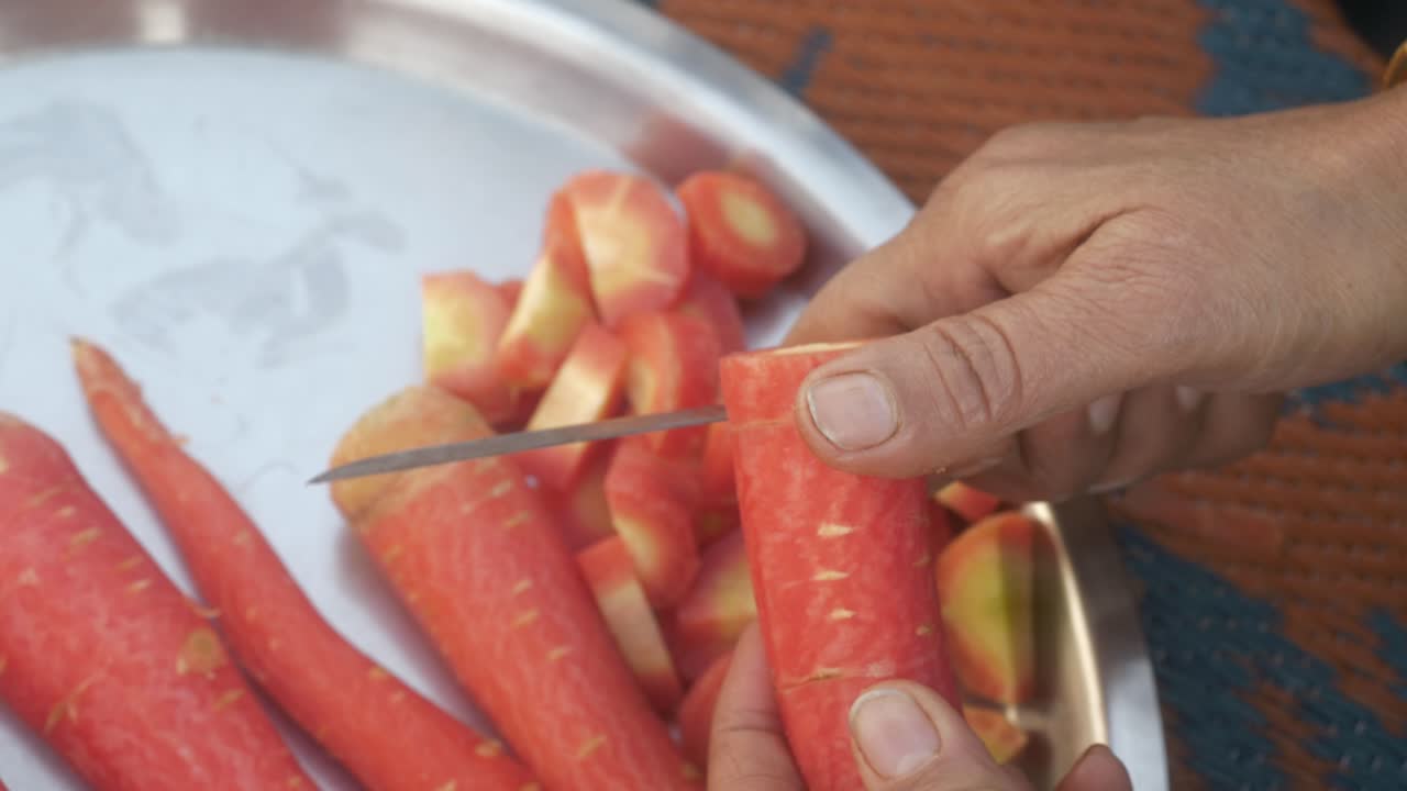 Closeup of hands cutting fresh orange carrots
