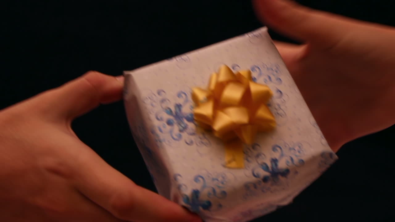 Manos intercambiando una pequeña caja de regalo envuelta