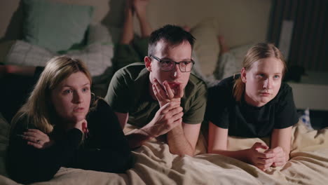 familia viendo la televisión en la cama