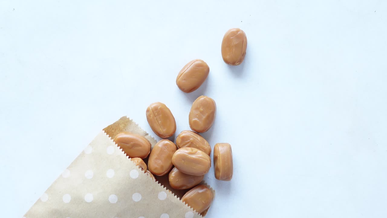 Caramel chocolate bar spilling from a paper packet on white ,