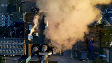 top aerial view of fumes coming from an industrial chimney near a residential area