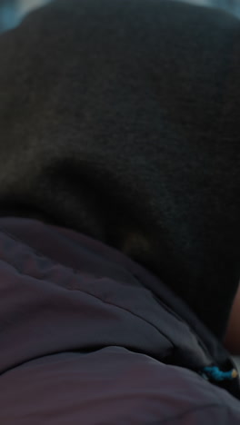 야외 스포츠 경기장에서 재과 모자를 입고 조하는 남자의 클로즈업, 한 오피스 빌딩과 도시 배경에 대한 집중과 결단력을 강조합니다.