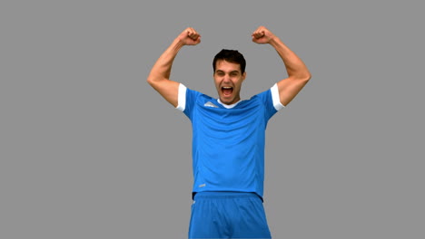 jugador de fútbol feliz levantando los brazos en la pantalla gris