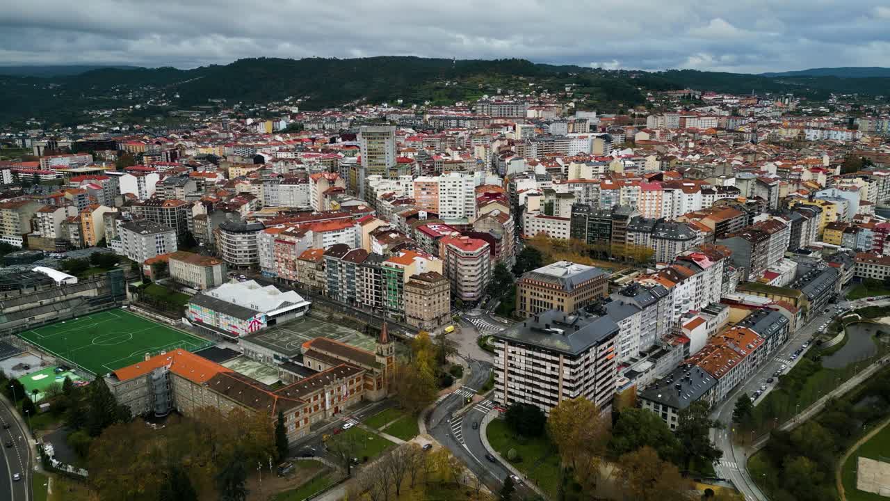Skyline della città di Ourense, Galizia, Spagna, sotto nuvole grigie con campo da calcio e condomini.