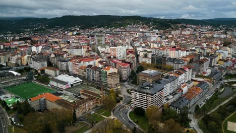 ourense, galicia, spain city skyline under grey clouds with football field and apartment buildings