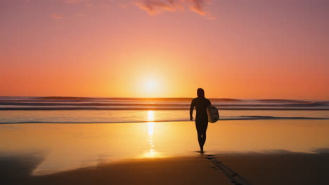 surfista caminando por la playa al atardecer