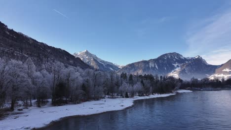 a serene winter landscape of walensee near weesen, switzerland, with snow-covered trees, calm waters, and majestic alpine peaks under a crisp blue sky.