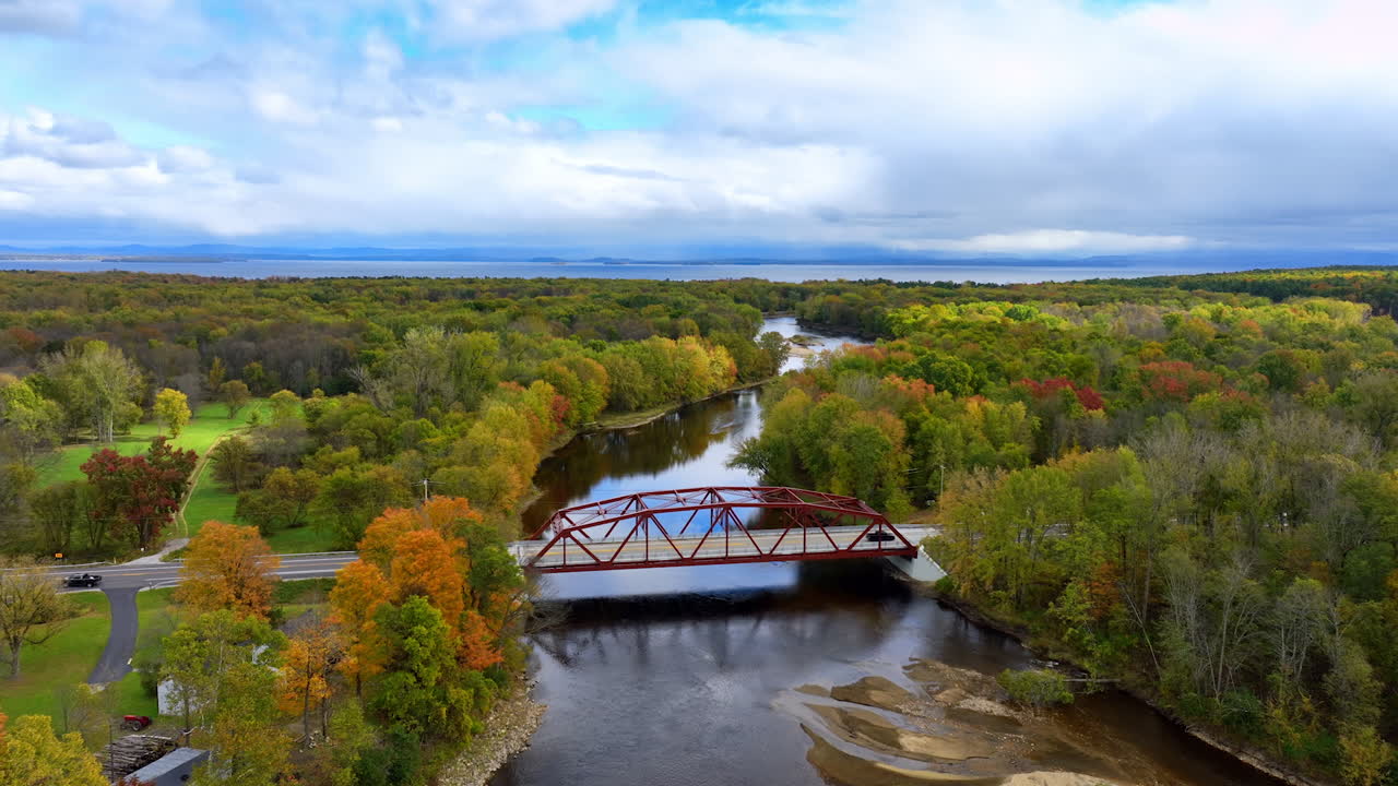 Approaching a little metal bridge crossing the narrow river. Black car crosses the bridge. Lovely nature of the north of New York state in the fall.