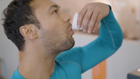 sportsman man drinking water at gym in slow motion -face close-up profile view