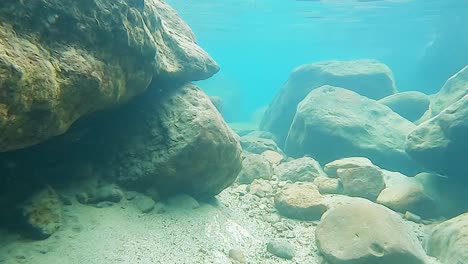 Rocas-En-El-Fondo-De-La-Cascada-Con-Agua-Azul-Clara-En-El-Día-Desde-El-ángulo-Frontal