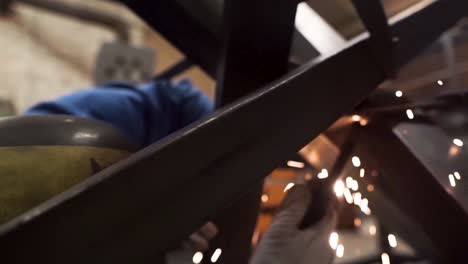 Worker-is-welding-metal-construction-in-the-factory,-there-are-sparks-in-the-shot