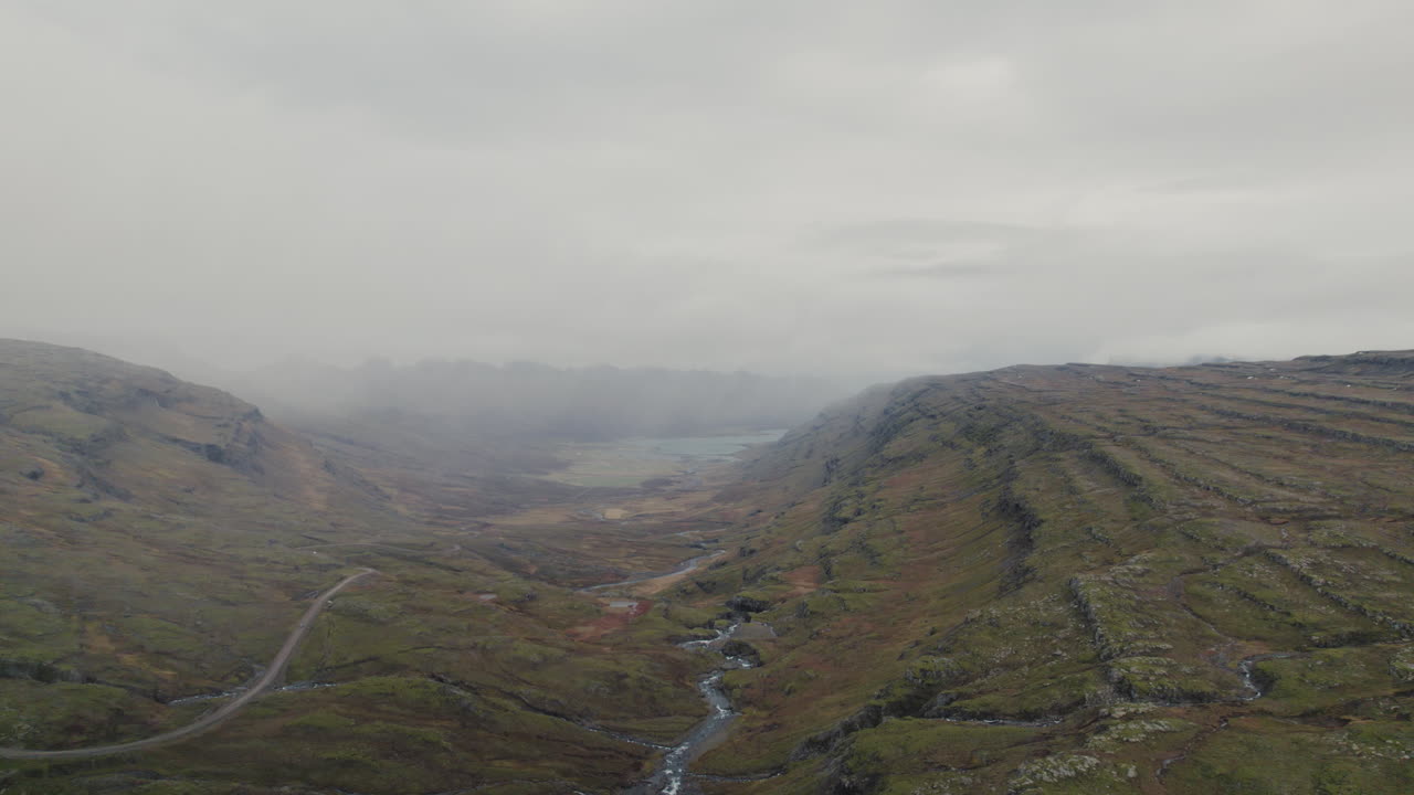 amplia antena de estepas montañosas, valle del río, mirando a la costa de islandia brumosa