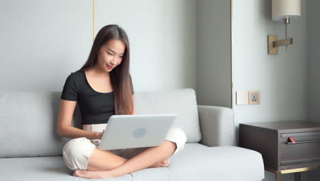 casual young woman sitting in sofa at home using laptop computer