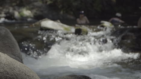 slow motion out of focus women in swimwear splashing in river