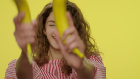 funny woman playing with banana and shooting like gun on yellow background