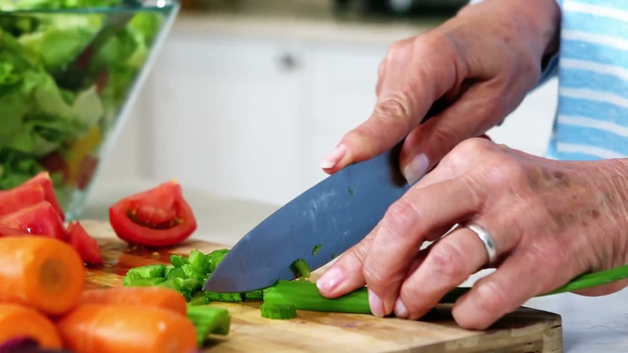 manos de una mujer mayor preparando ensalada de verduras