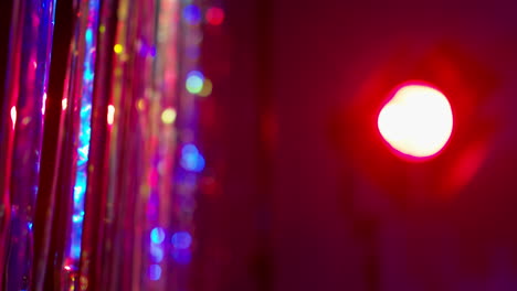 Shot-Of-Defocused-Tinsel-Curtain-And-Spotlight-In-Night-Club-Or-Disco-With-Reflected-Sparkling-Lights