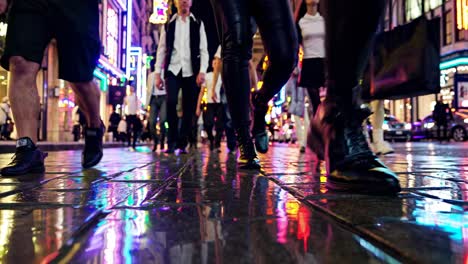 low-angle video shot of bustling city street at night, capturing vibrant neon reflections on wet