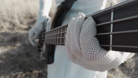 close up man playing electric guitar while wearing white gloves and clothing outside