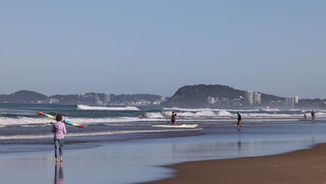 person carrying kayak into ocean waves