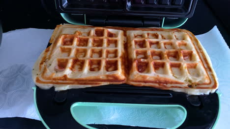 cooking waffles in a waffle maker,fresh dough in a waffle maker baked gold