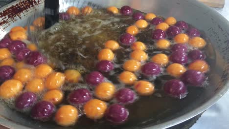 cooking quail candy eggs or turtle eggs sweets in big pan with hot oil, thai traditional dessert snack made from cassava flour (tapioca starch) and sweet potato at the market. 4k footage.