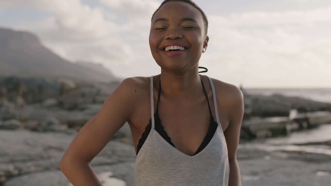 ritratto di una orgogliosa donna afroamericana sulla spiaggia che ride felice e sicura di sé