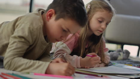 niño coloreando cuadros en el suelo. hermosos hermanos pintando en cuadernos de bocetos en casa