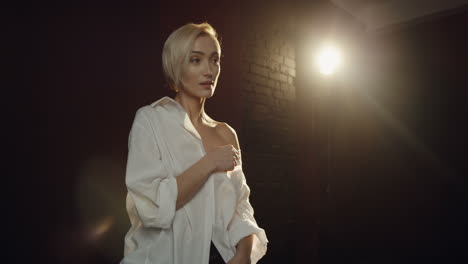 close-up view of caucasian young female model posing in the dark studio with smoke while the photographer taking shots of her