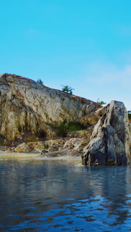 a large rock sits on the shore of a calm sea