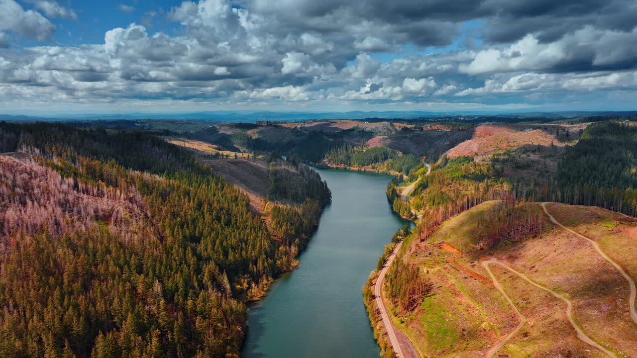 Stunning nature with mountains and river in the middle. Dramatic cloudscape covering the sky above the mountains. Aerial view.